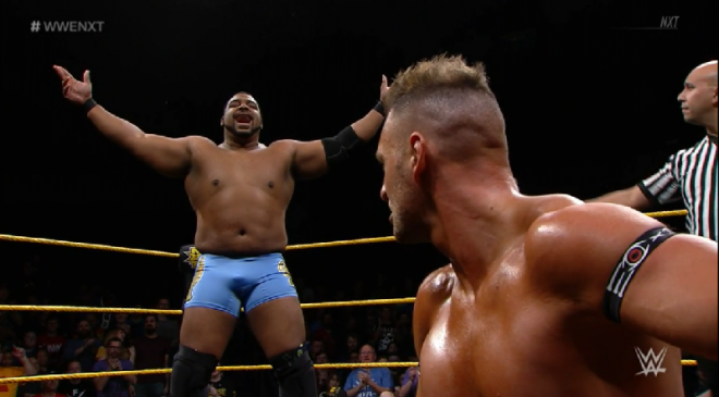 Lee holds his hands high in the air, after evading Dijakovic, who looks on from bended kenee