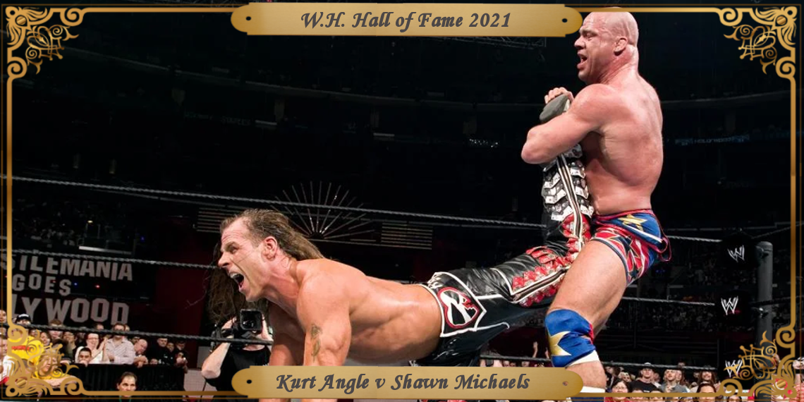 Angle holds Michaels in the ankle lock. Michaels is parallel to the mat, perched up on his elbows in pain.