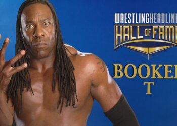 Booker T glares at the camera with a serious face, holding up his right hand with fingers and thumb outstretched to show "5-time champion". He is shirtless and wearing his hair in dreadlocks that drape over his pec muscles.