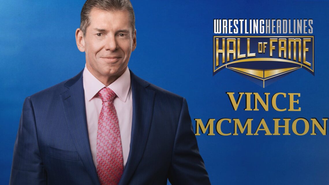 Vince McMahon is smirking at the camera wearing a navy suit with a rose coloured dress shirt and a red and light yellow pattern tie.