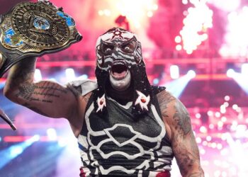 Penta raises a championship belt in a WWE arena