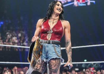 Rhea Ripley stands in a WWE ring holding a championship belt